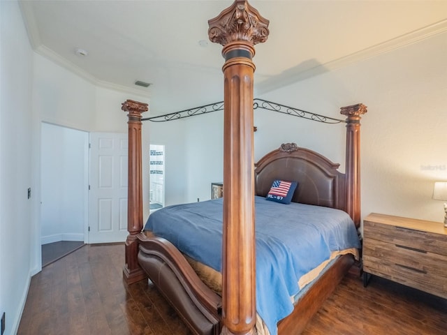 bedroom with dark wood-type flooring, crown molding, and decorative columns