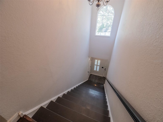 stairway with wood-type flooring and an inviting chandelier