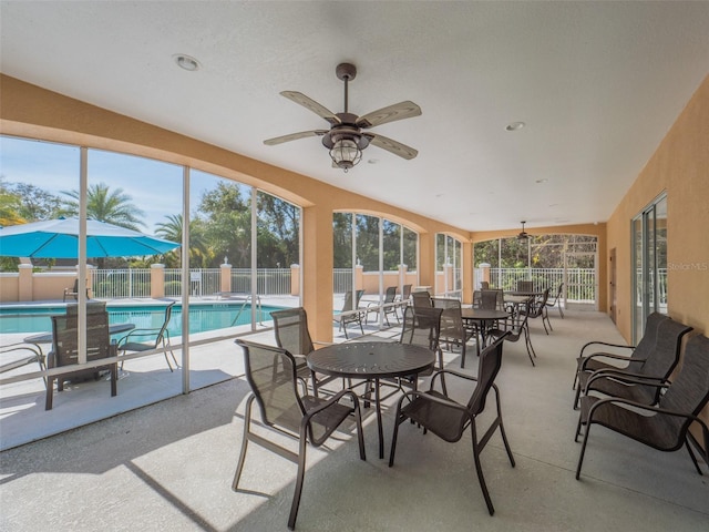 sunroom / solarium with ceiling fan and a pool