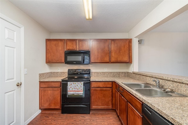 kitchen featuring sink, a textured ceiling, dark hardwood / wood-style floors, and black appliances