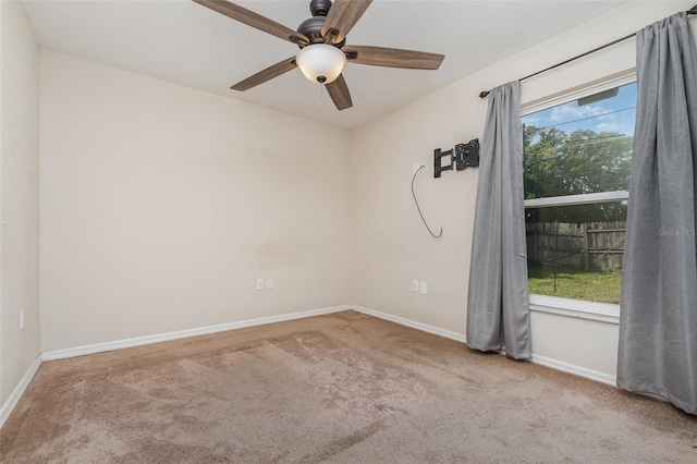 carpeted spare room featuring a wealth of natural light and ceiling fan