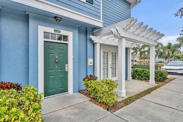 view of exterior entry with french doors and a pergola