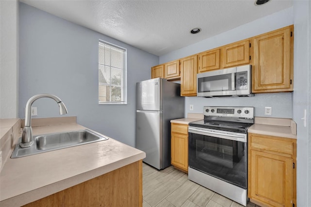 kitchen featuring sink, stainless steel appliances, a textured ceiling, and light brown cabinets