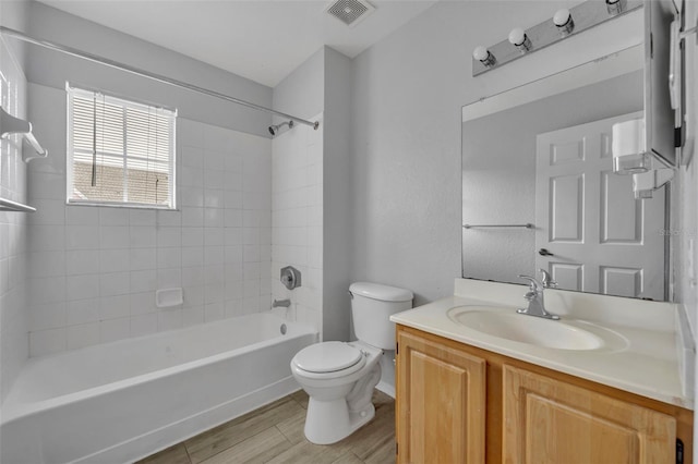 full bathroom with vanity, hardwood / wood-style flooring, tiled shower / bath combo, and toilet