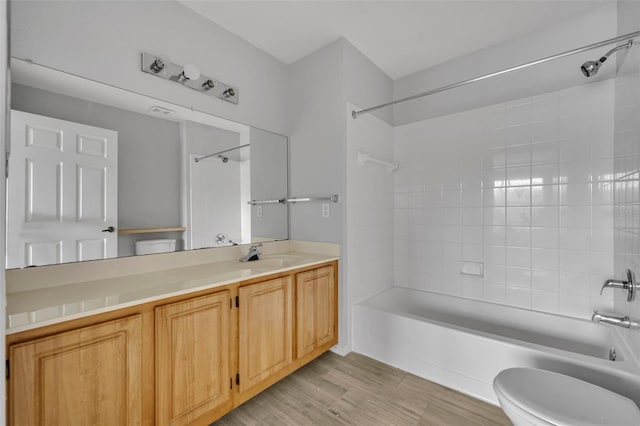 full bathroom featuring hardwood / wood-style flooring, tiled shower / bath, vanity, and toilet