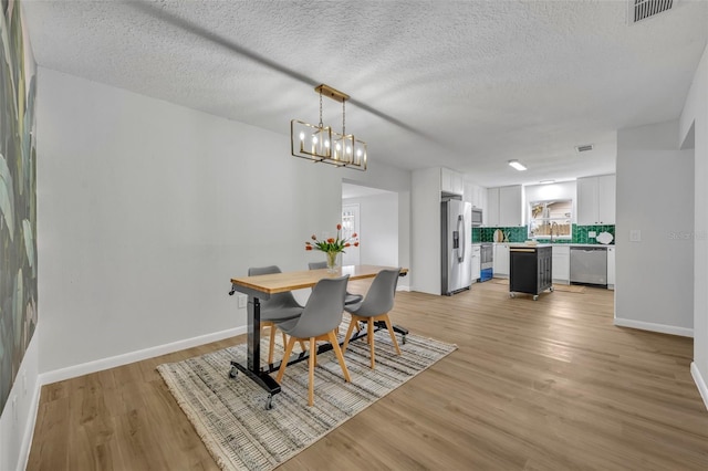 dining area featuring sink, light hardwood / wood-style floors, and a textured ceiling