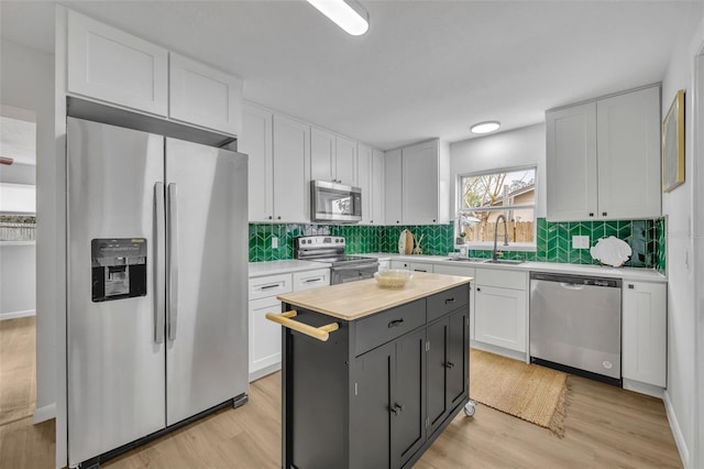 kitchen featuring sink, light hardwood / wood-style flooring, white cabinetry, stainless steel appliances, and a center island