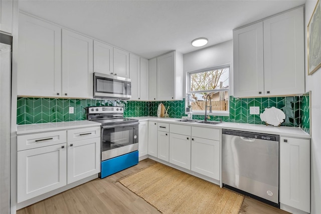 kitchen featuring sink, stainless steel appliances, light hardwood / wood-style floors, and white cabinets