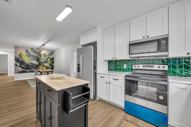 kitchen featuring stainless steel appliances, white cabinets, light hardwood / wood-style floors, and decorative backsplash