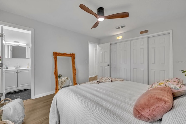 bedroom featuring sink, ensuite bath, wood-type flooring, a closet, and ceiling fan