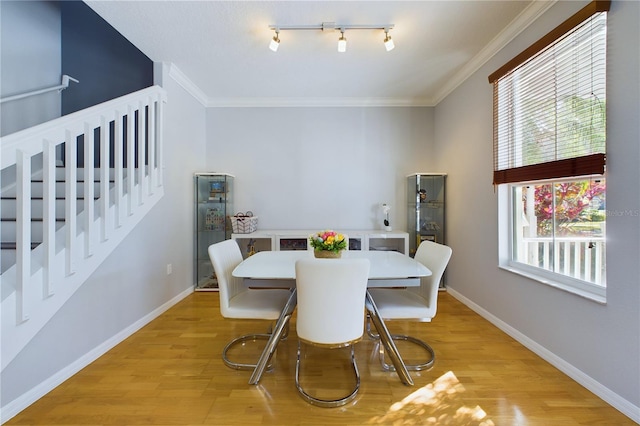 dining room with ornamental molding, rail lighting, and light hardwood / wood-style flooring