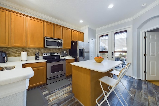 kitchen featuring appliances with stainless steel finishes, dark hardwood / wood-style floors, ornamental molding, a center island, and french doors