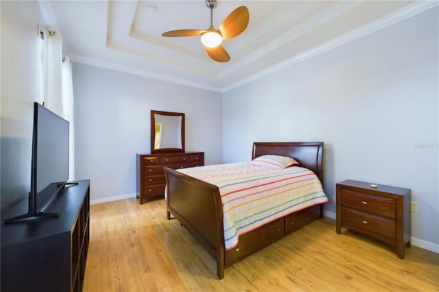 bedroom featuring crown molding, light hardwood / wood-style flooring, a raised ceiling, and ceiling fan