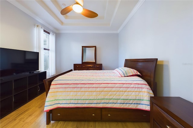 bedroom featuring crown molding, light hardwood / wood-style floors, a raised ceiling, and ceiling fan