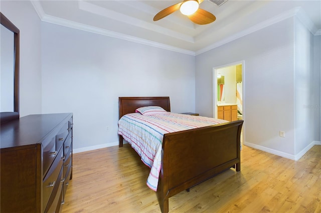 bedroom with light hardwood / wood-style flooring, ceiling fan, connected bathroom, a tray ceiling, and ornamental molding