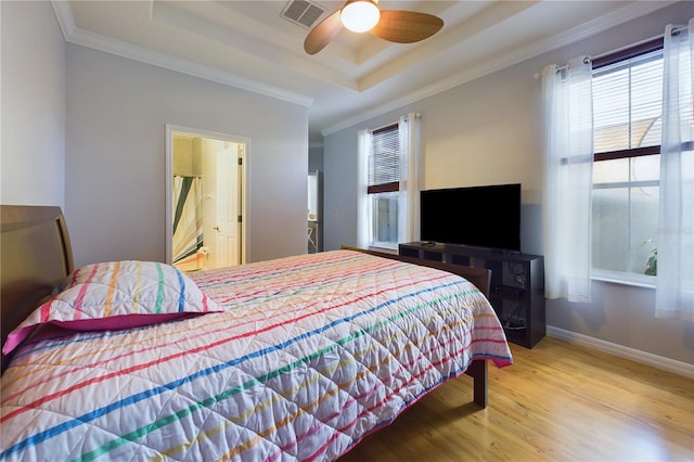 bedroom featuring hardwood / wood-style flooring, crown molding, ceiling fan, and a tray ceiling