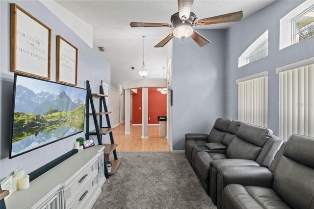 living room featuring ceiling fan, light colored carpet, and a towering ceiling