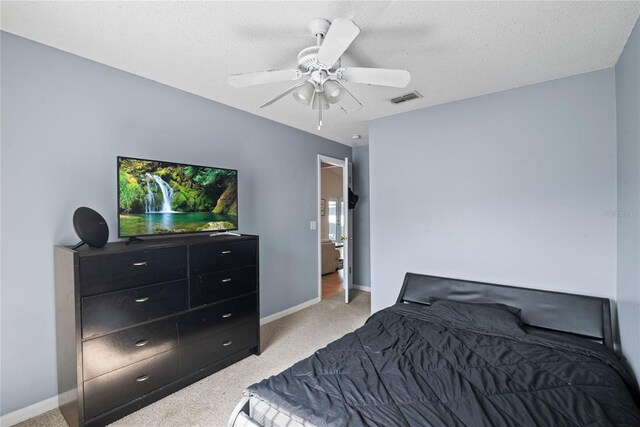 carpeted bedroom with ceiling fan and a textured ceiling