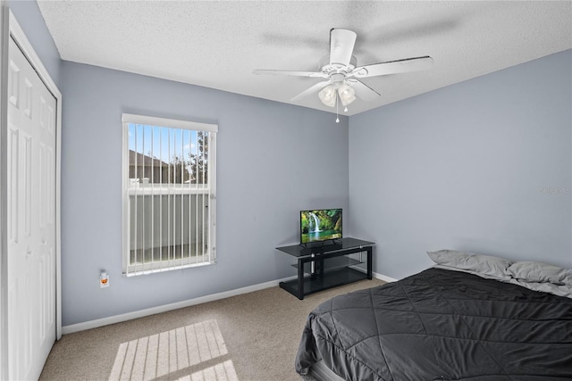 carpeted bedroom featuring ceiling fan, a textured ceiling, and a closet
