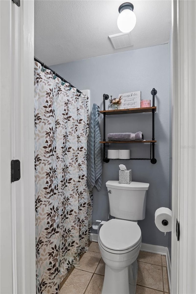 bathroom featuring tile patterned floors, a textured ceiling, and toilet