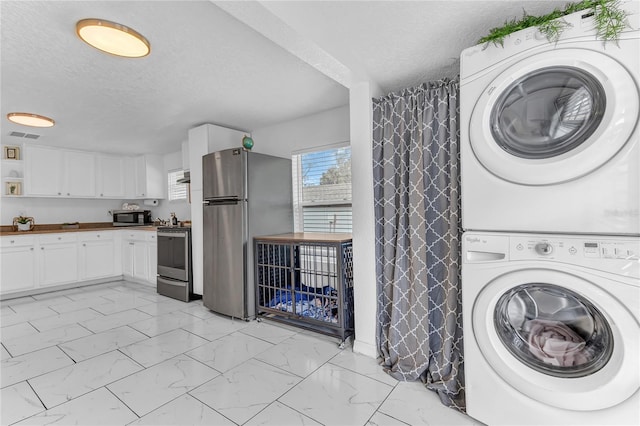 washroom featuring stacked washer / drying machine and a textured ceiling