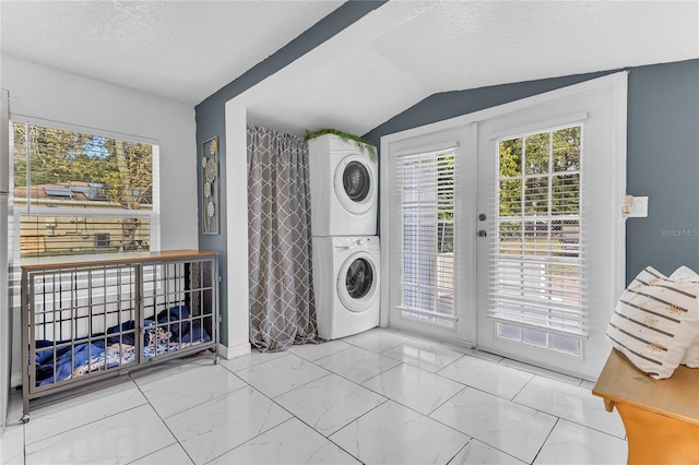 washroom featuring french doors, stacked washer and dryer, and a textured ceiling