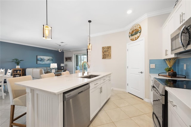 kitchen featuring appliances with stainless steel finishes, decorative light fixtures, white cabinetry, an island with sink, and sink