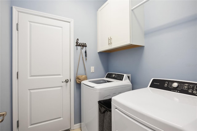 clothes washing area with cabinets and washer and dryer