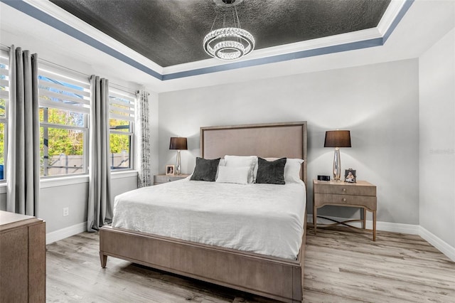 bedroom with ornamental molding, light hardwood / wood-style floors, and a raised ceiling