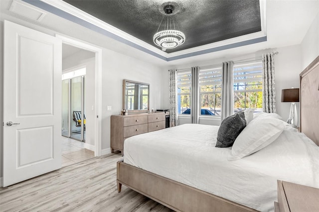 bedroom with a raised ceiling, ornamental molding, a textured ceiling, and light hardwood / wood-style flooring