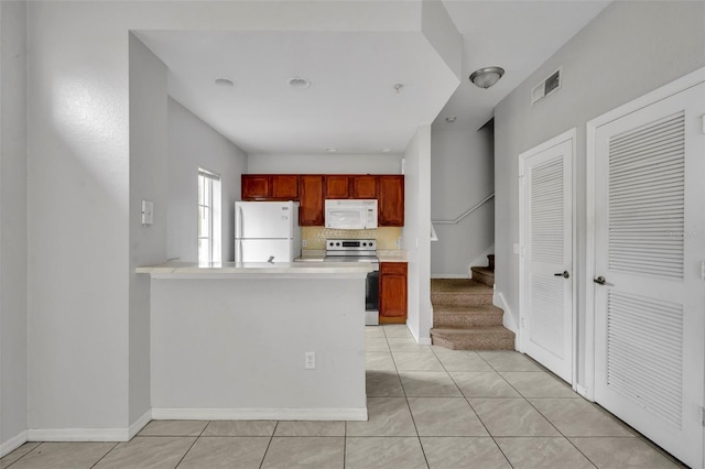 kitchen with tasteful backsplash, light tile patterned floors, white appliances, and kitchen peninsula