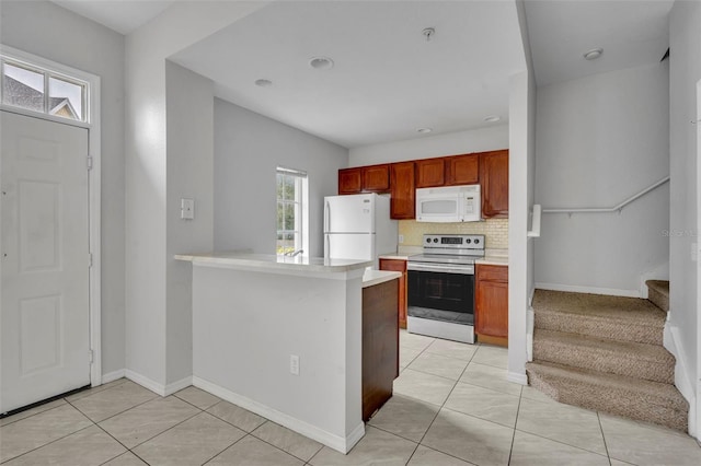 kitchen with white appliances, a healthy amount of sunlight, kitchen peninsula, and backsplash