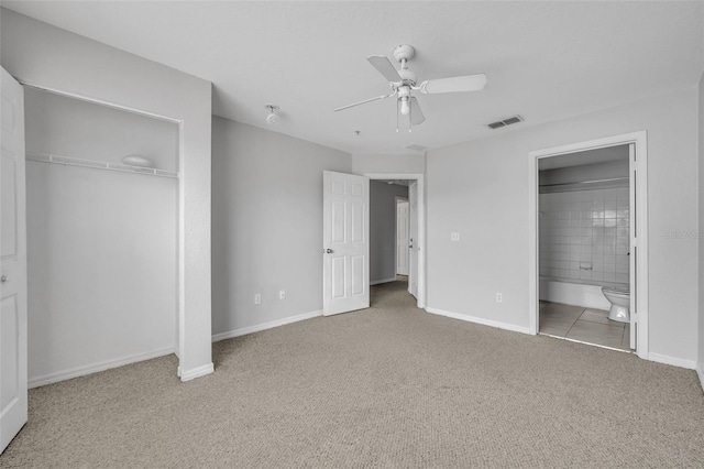 unfurnished bedroom featuring ceiling fan, a closet, ensuite bath, and carpet