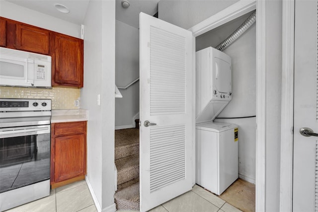 kitchen with stacked washing maching and dryer, light tile patterned flooring, decorative backsplash, and stainless steel electric range oven