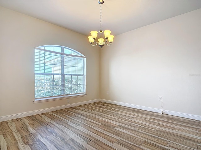 unfurnished room featuring a notable chandelier and light hardwood / wood-style flooring