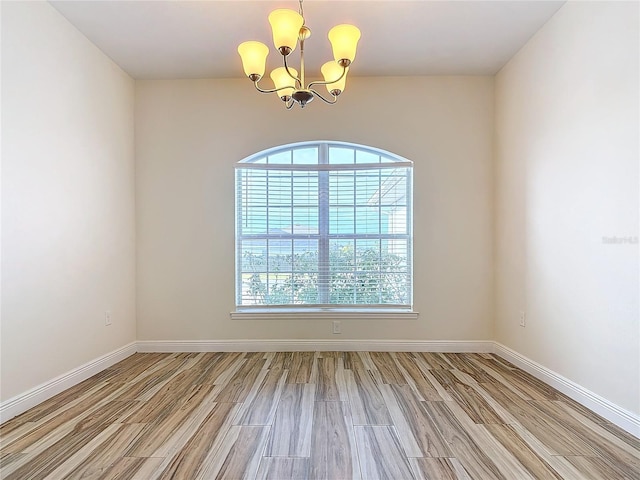 unfurnished room with light hardwood / wood-style flooring and a notable chandelier