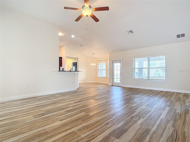 unfurnished living room with hardwood / wood-style flooring, lofted ceiling, plenty of natural light, and ceiling fan