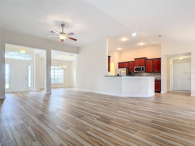 unfurnished living room with vaulted ceiling and ceiling fan with notable chandelier