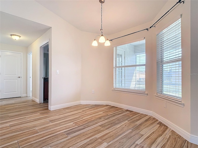 spare room with an inviting chandelier and light wood-type flooring