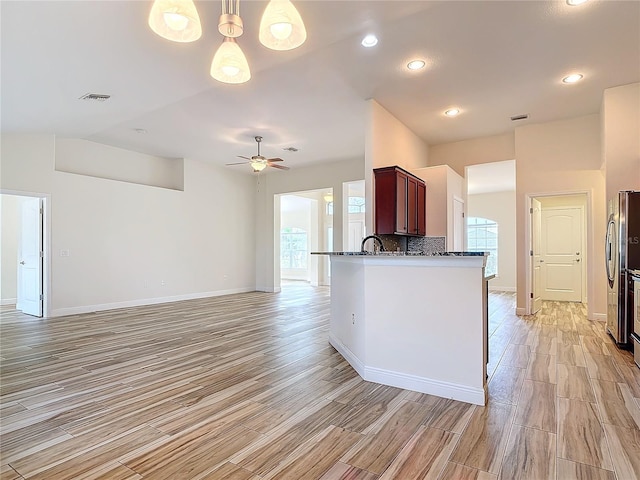 kitchen with stainless steel fridge, kitchen peninsula, pendant lighting, ceiling fan, and decorative backsplash