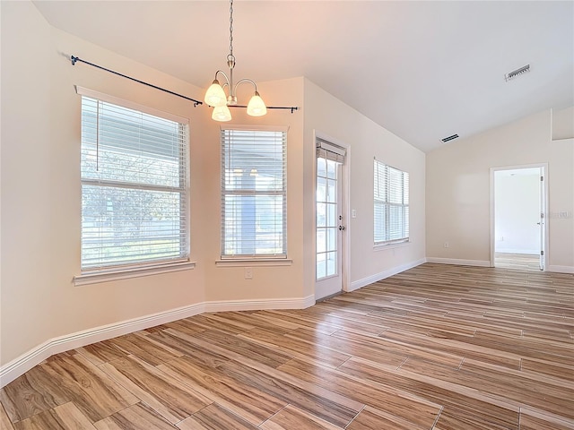 unfurnished dining area with an inviting chandelier, lofted ceiling, and hardwood / wood-style floors