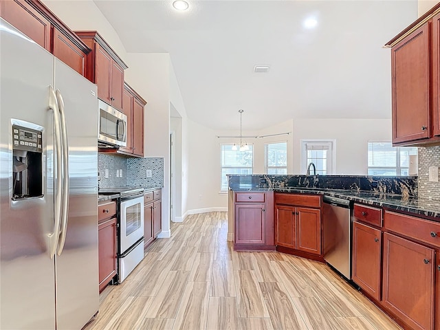 kitchen with hanging light fixtures, backsplash, dark stone counters, and appliances with stainless steel finishes