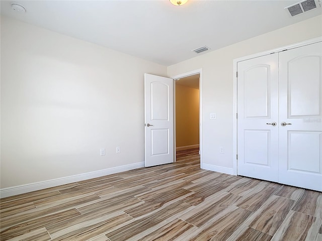 unfurnished bedroom featuring light wood-type flooring and a closet