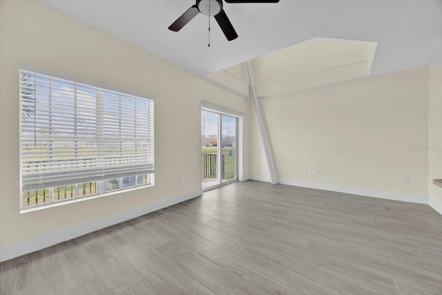 spare room with ceiling fan, vaulted ceiling, and light hardwood / wood-style floors