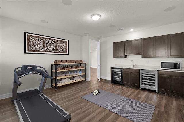 interior space featuring sink, dark hardwood / wood-style floors, beverage cooler, and a textured ceiling