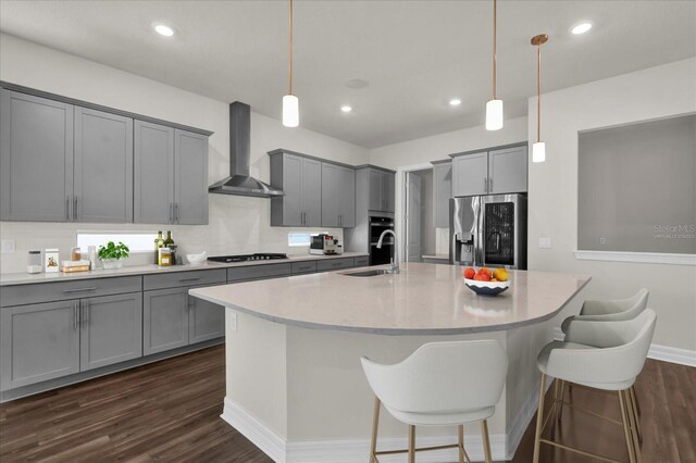 kitchen featuring hanging light fixtures, sink, wall chimney range hood, and black appliances