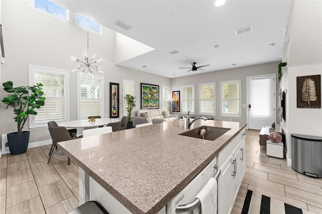 kitchen with sink, plenty of natural light, an island with sink, white cabinets, and stainless steel dishwasher