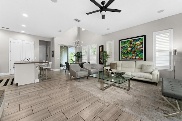 living room with sink, ceiling fan with notable chandelier, and a wealth of natural light