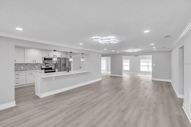 kitchen featuring tasteful backsplash, white cabinetry, stainless steel appliances, crown molding, and light wood-type flooring