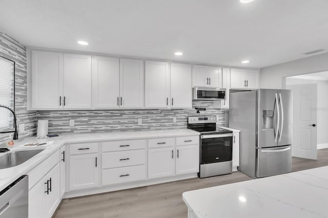 kitchen with light stone counters, stainless steel appliances, sink, and white cabinets